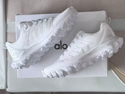 Pair of white Alo sneakers shown at an angle on a box.