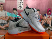 Angled view of gray and white Nike basketball shoes showing side panels, laces, and orange outsoles.