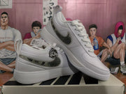 Angled view of the white sneaker pair highlighting the patterned swoosh, laces, heel structure, and Chapter One detailing.