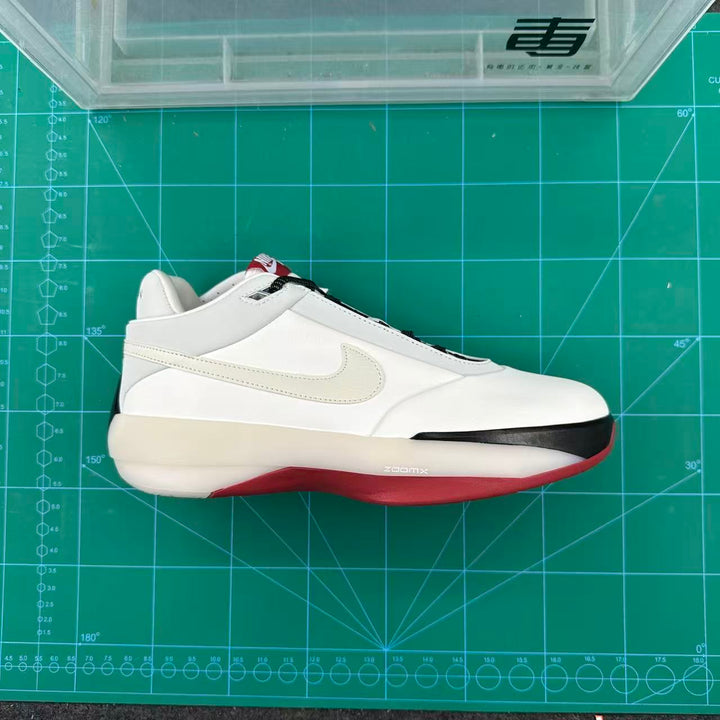 Side view of white Jordan basketball sneakers with black and red accents on a green cutting mat.