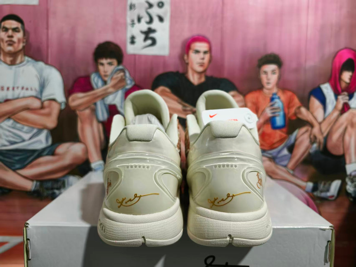 Rear view of cream Nike KD basketball shoes showing the padded collars, heel details, and gold script accents.