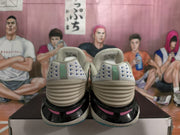 Rear view of the sneaker pair showing textured heel panels, blue triangular details, black-and-pink midsole accents, and speckled soles.