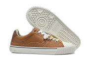 Brown sneaker beside its patterned off-white outsole, showing the side profile and toe cap.