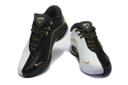 Pair of black and white Nike sneakers shown from the front with gold accents and patterned laces.