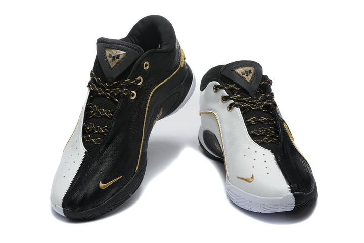 Pair of black and white Nike sneakers shown from the front with gold accents and patterned laces.