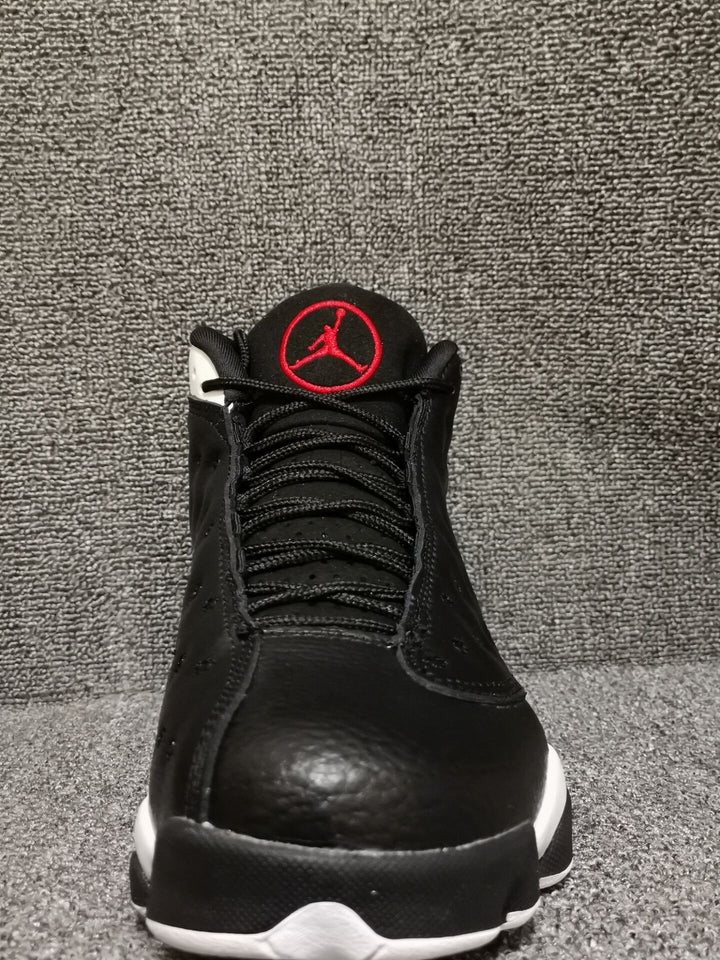 Front view of black high-top sneakers with red tongue emblem and white outsole accents