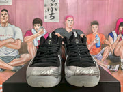 Front view showing black laces and collars, silver textured toe boxes, and tongue branding.