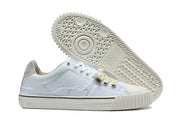 White low-top sneaker pair with a close view of the patterned outsole and cream-colored sidewalls.
