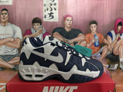 Side view of navy and white Nike sneakers with layered panels and a chunky sole