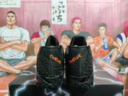 Rear view of the black sneakers showing orange heel lettering and textured heel panels.