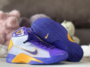 Pair of purple and gold high-top sneakers shown from the side with one outsole facing upward.