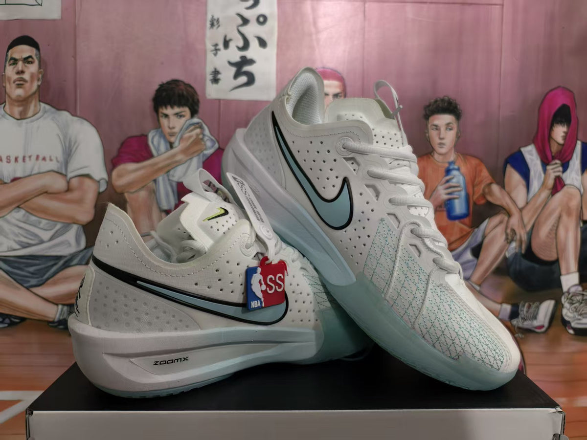 Pair of white Nike basketball sneakers displayed on a box, showing light blue-green Swoosh accents, perforated uppers, and ZoomX midsole branding.