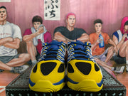 Front view of royal blue and yellow Nike sneakers with black mesh toe panels, blue laces, and white trim.