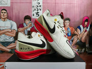 Angled view of the sneakers highlighting the black Swoosh, olive heel panel, decorative symbols, and red sole structure.