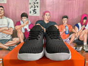 Front view of black Nike sneakers with patterned uppers, black laces, and white ridged soles.