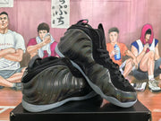 Pair of black Nike basketball sneakers with a reflective sculpted upper and translucent soles, displayed against an illustrated basketball backdrop.