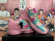 Pair of pink basketball shoes with colorful patterned panels, bright green laces, and a black hanging charm.