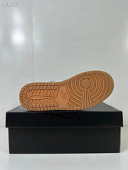 Gum-colored outsole displayed above a black shoe box, showing circular forefoot traction and segmented tread.