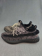 Side view of black Yeezy 350 V2-style sneakers with contrasting knit details and a black side band.