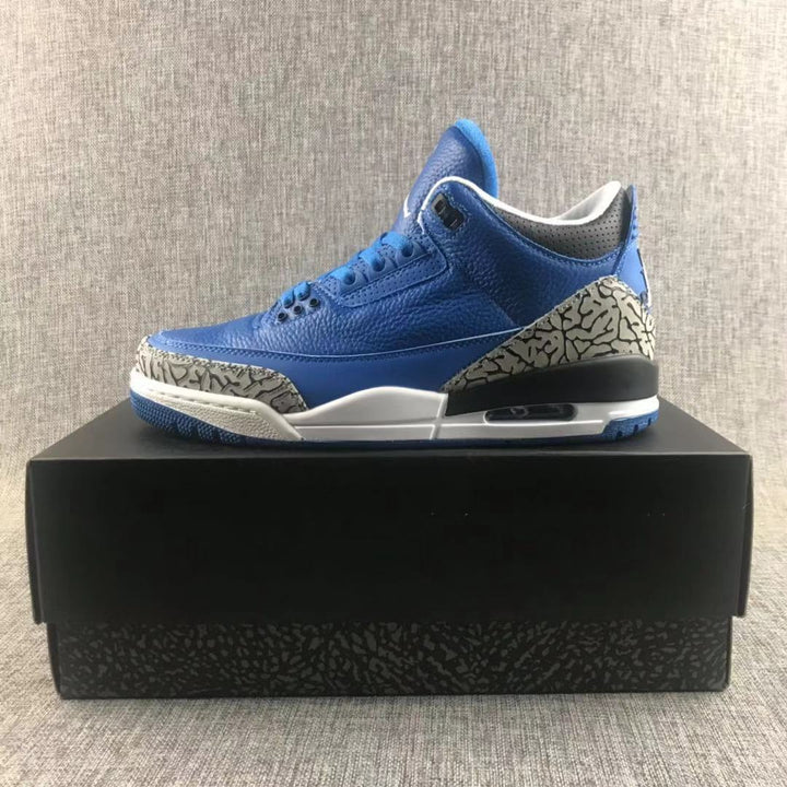 Side profile of blue Jordan Air Jordan 3 sneakers displayed on a black shoebox.
