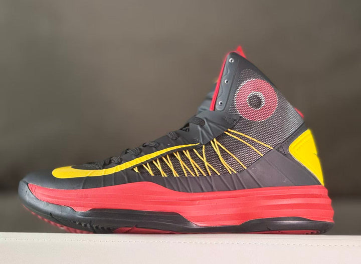 Side view of a dark high-top basketball shoe with yellow details and a red midsole