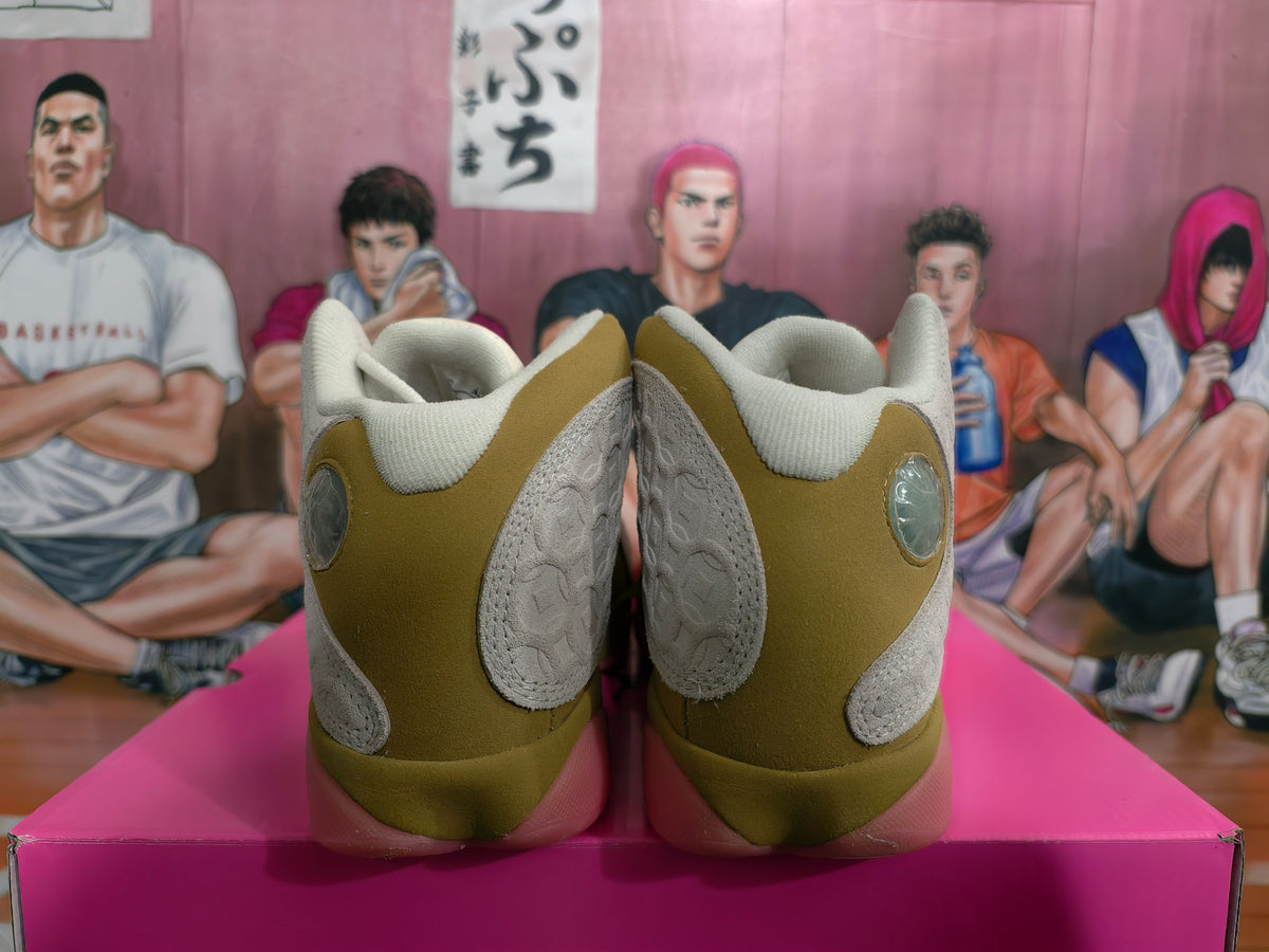 Rear view of olive and cream Jordan sneakers with circular heel accents and pink translucent soles on a box.