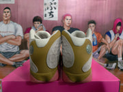 Rear view of olive and cream Jordan sneakers with circular heel accents and pink translucent soles on a box.
