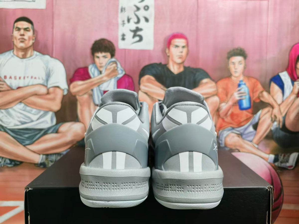 Rear view of grey Nike basketball sneakers showing white heel accents, textured midsoles, and a basketball-themed illustrated backdrop.