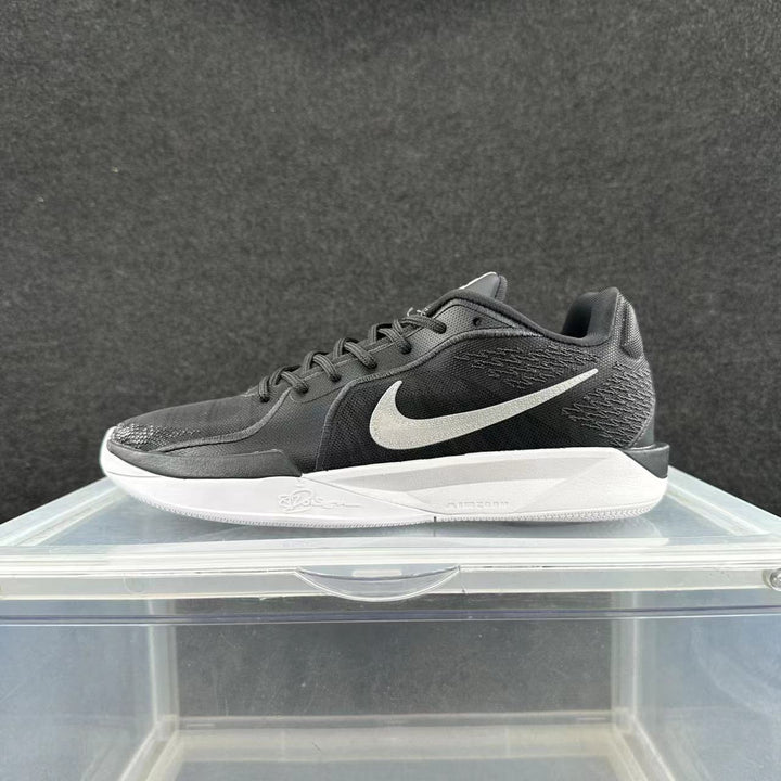 Side view of a black Nike low-top basketball sneaker with a white Swoosh and white midsole.