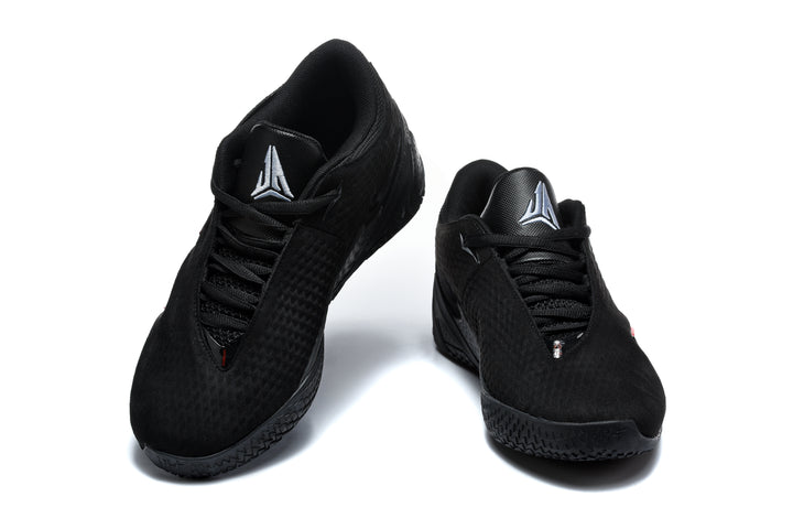 Pair of black low-top sneakers shown from the front with silver-tone tongue emblems