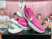 Pair of pink and white Nike basketball sneakers displayed on a black shoe box, showing the textured upper, white Swoosh, and translucent heel.