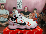 Side view of a pink and white Nike basketball sneaker with a black Swoosh, red-orange graphic accents, white laces, and a textured outsole.