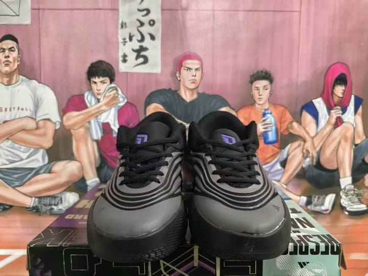 Pair of black and gray Adidas sneakers shown from the front, with black laces and layered gray detailing.