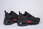 Pair of black sneakers with red side accents, shown in profile.