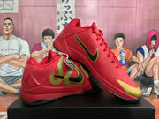 Angled view of two red Nike basketball sneakers showing the gold-and-black side detailing, Nike swoosh, laces, and black outsole.