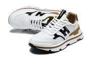 Pair of white lace-up sneakers with glossy black side panels, perforated toes, and tan-gold collar accents.