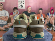 Rear view of coconut-milk and teal Nike basketball sneakers showing brown heel panels, contrasting heel details, and textured outsole sections.