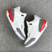 Two sneakers displayed at an angle, showing red heel panels and grey patterned overlays