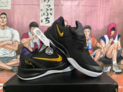 Angled view of black Nike basketball shoes with yellow Swooshes, purple accents and white outsoles.