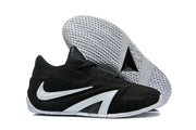 Black basketball shoes shown from the side with one shoe lifted to reveal the textured white outsole.