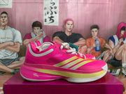 Side profile showing the pink mesh-style upper, light-colored stripes, layered midsole, and white outsole.
