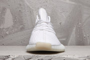 Front view of a white sneaker showing the lace arrangement, rounded toe, and translucent sole detail.