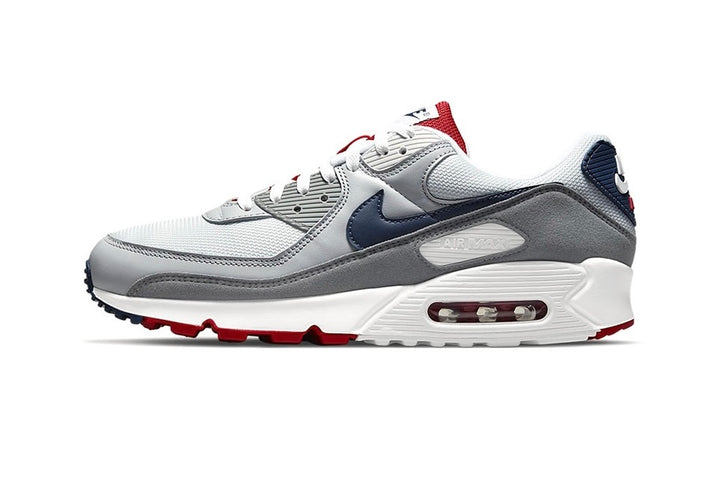 Side view of a white, grey, navy and red Nike Air Max sneaker.