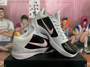 Angled view of the white and black basketball sneakers, highlighting the glossy black side panels, laces, and red-edged Swoosh branding.