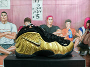 Side view of a gold and black Nike basketball sneaker with a textured metallic-look upper and black outsole.