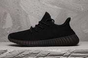 Side profile of a black low-top sneaker with a textured upper and dark ribbed outsole.