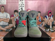 Front view of green and gray high-top basketball sneakers with teal laces, dark blue tongue emblems, and textured uppers.