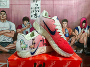 Angled view showing the pink and red textured uppers, illustrated side graphics, navy side branding and light-colored outsole.