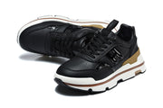 Pair of black low-top sneakers shown from an angled top view, highlighting the perforated toes and chunky white soles.