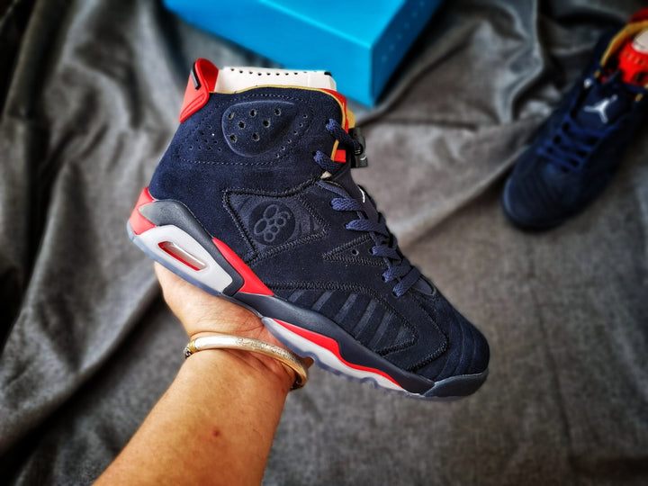Close-up view of a navy high-top Jordan 6 sneaker with red accents, a white midsole, and a visible heel cushioning window.